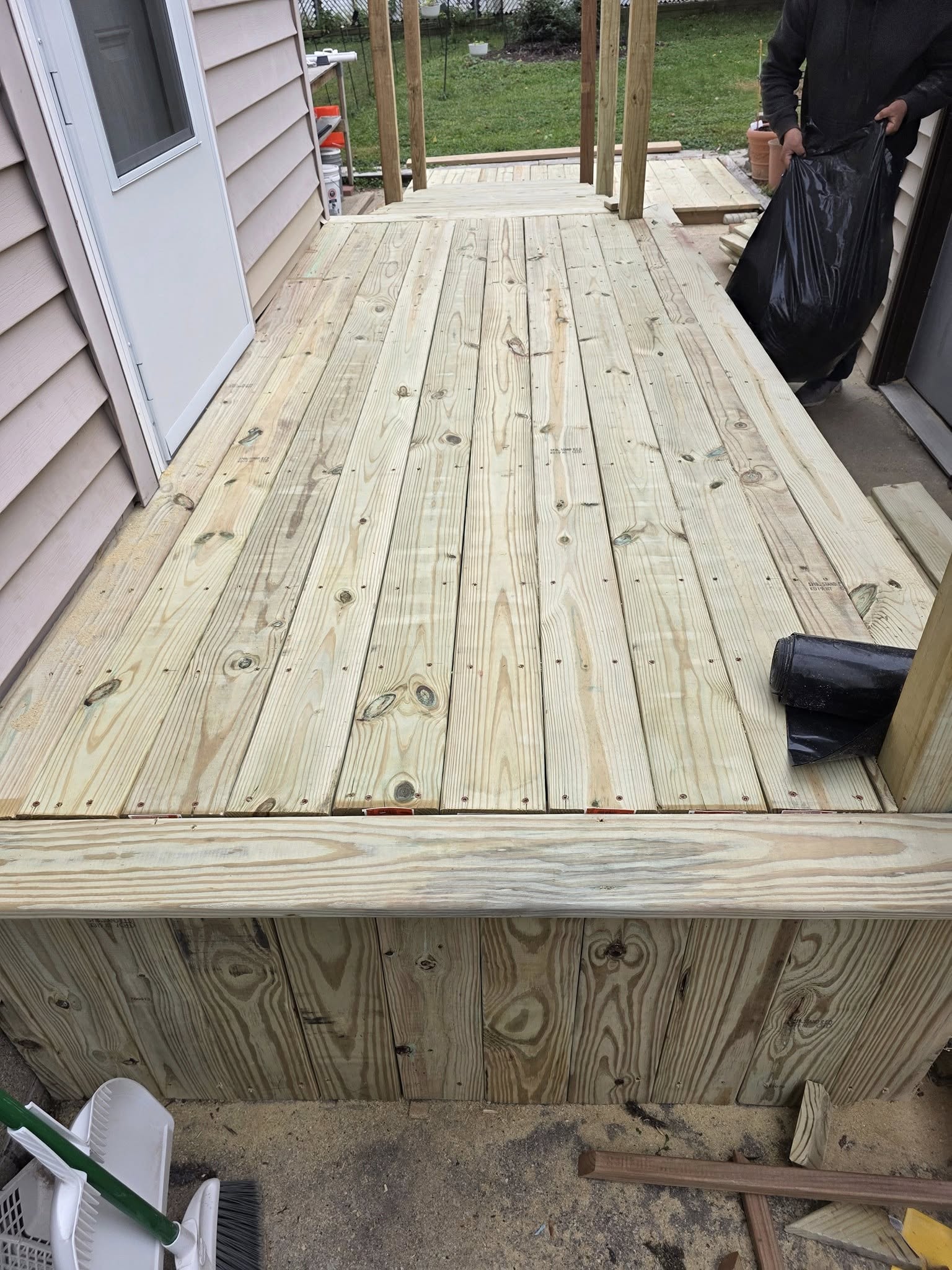 A newly built pressure-treated wood deck behind a home