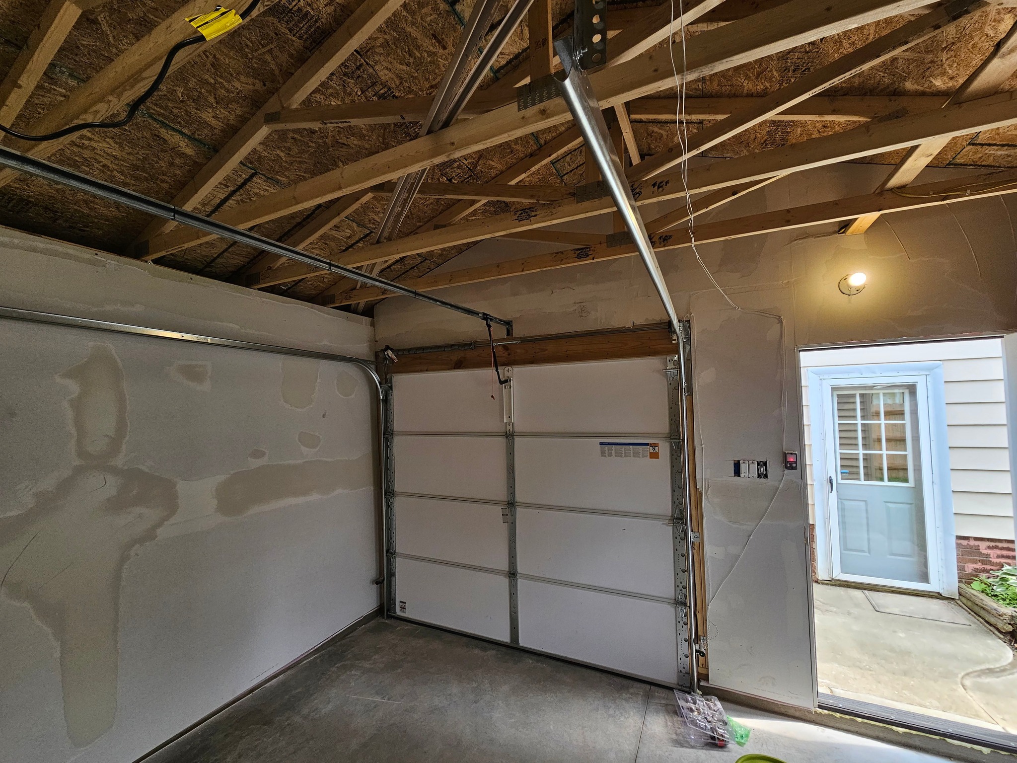 A garage interior finished with fresh drywall and a new door