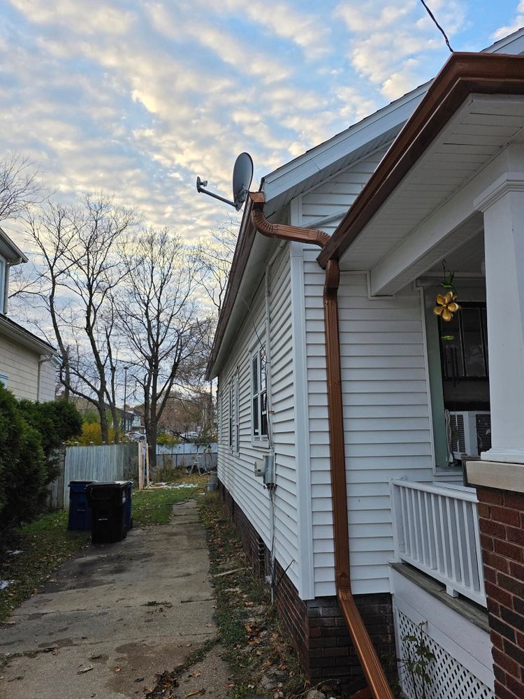New seamless downspouts and gutters on a white sided house
